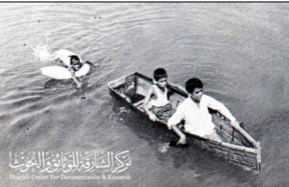 أطفال في خور الشارقة عام 1970 يلعبون في قارب صغير